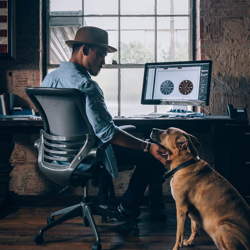 Man working at his desk while petting his dog