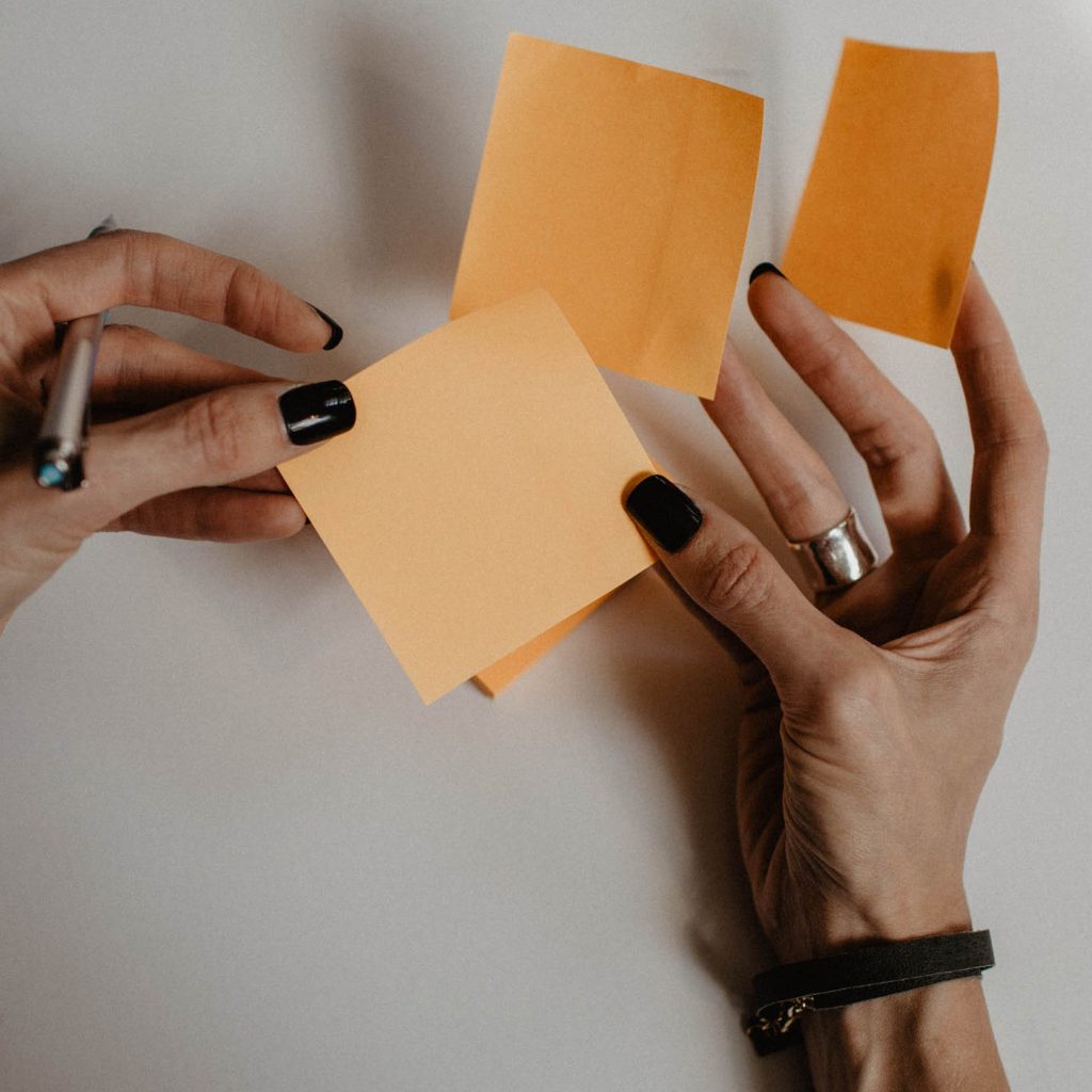 hands holding orange sticky notes